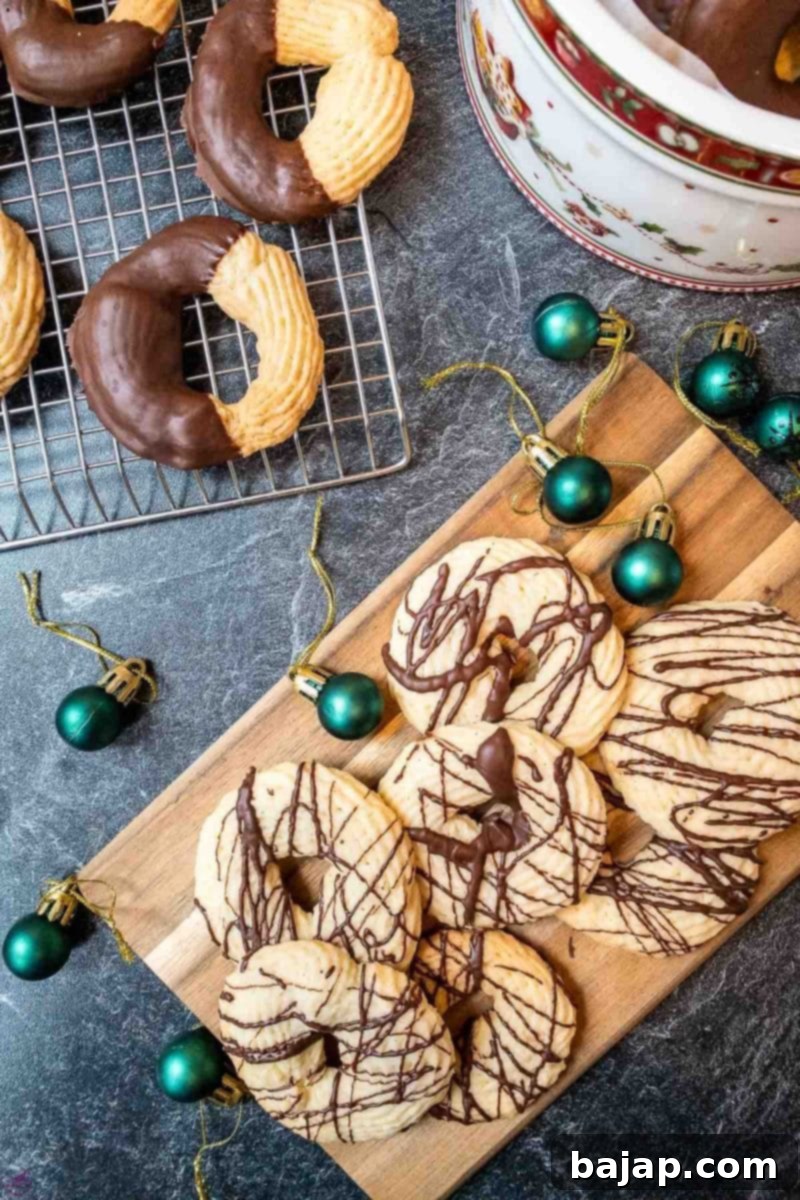Butter cookies drizzled with dark chocolate sauce, showcasing their golden edges and smooth chocolate coating.