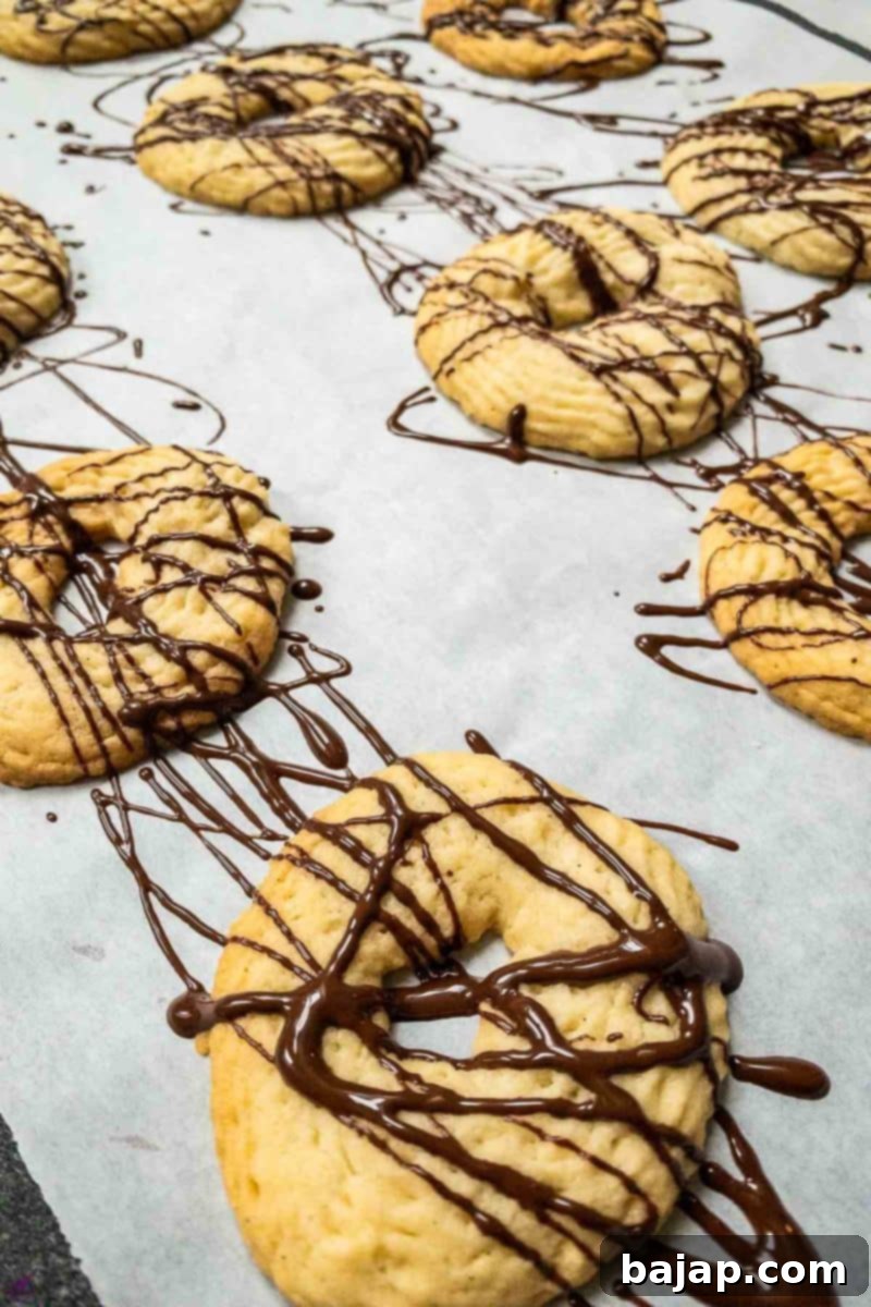 Butter cookies artfully drizzled with melted dark chocolate couverture, showing a decorative finishing touch.