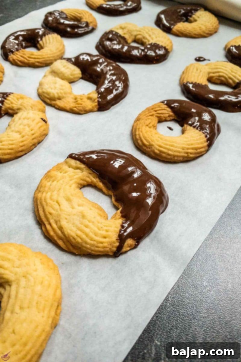Butter cookies dipped halfway into dark chocolate couverture, showcasing the distinct chocolate coating.