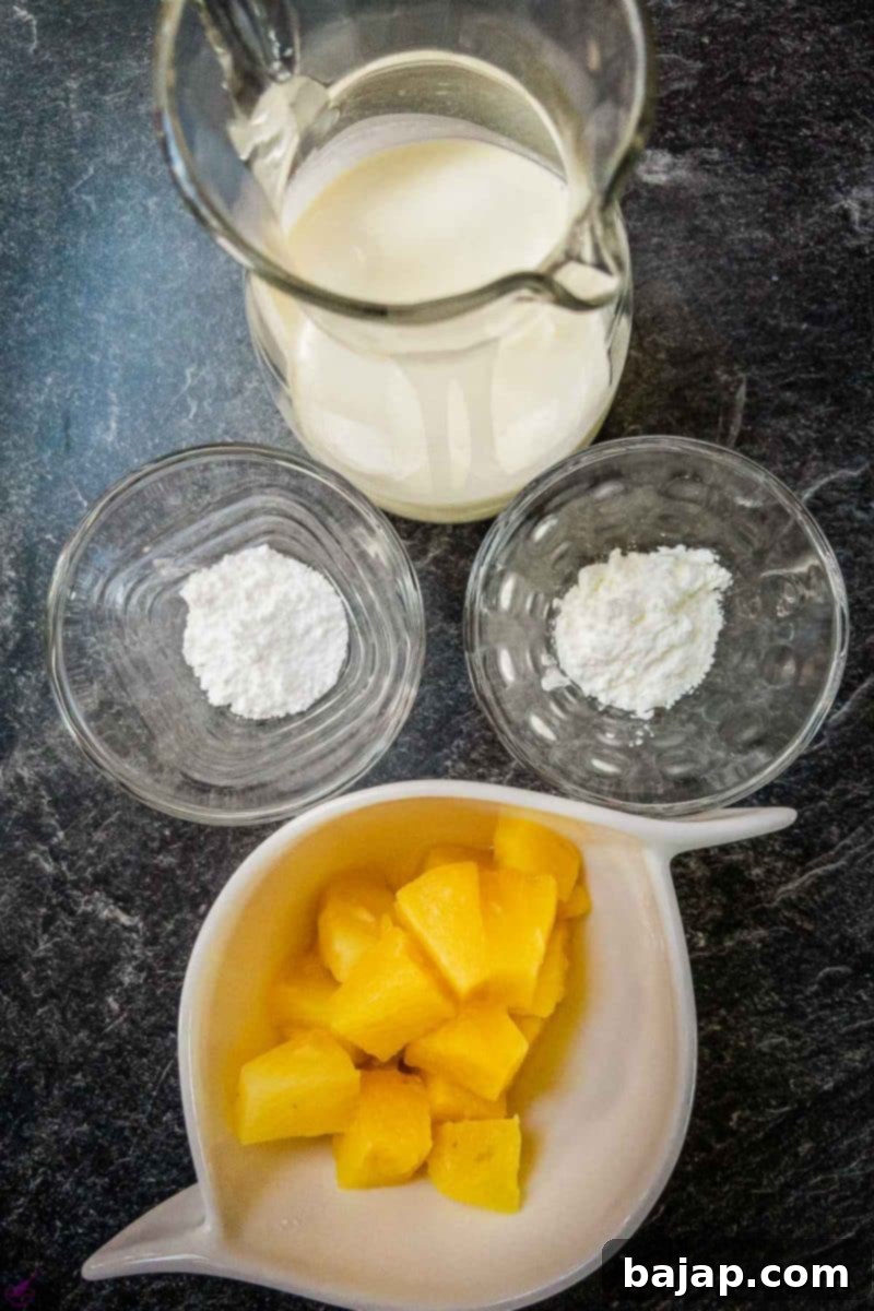 Ingredients for no bake pineapple dessert. Whipped cream, pineapple chunks, powdered sugar, and cornstarch laid out on a dark surface.