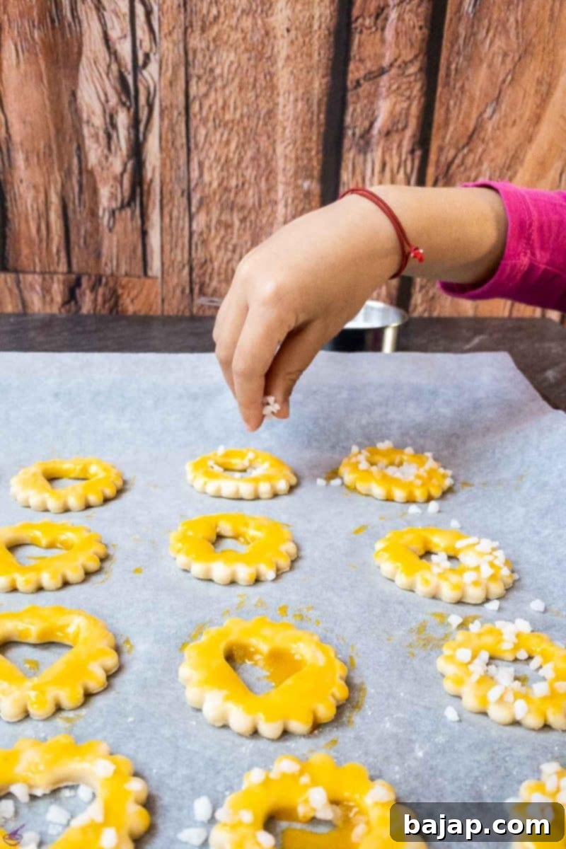 Cut out sour cream cookies before baking. Spread with egg yolk. Sprinkled with nib sugar. 
