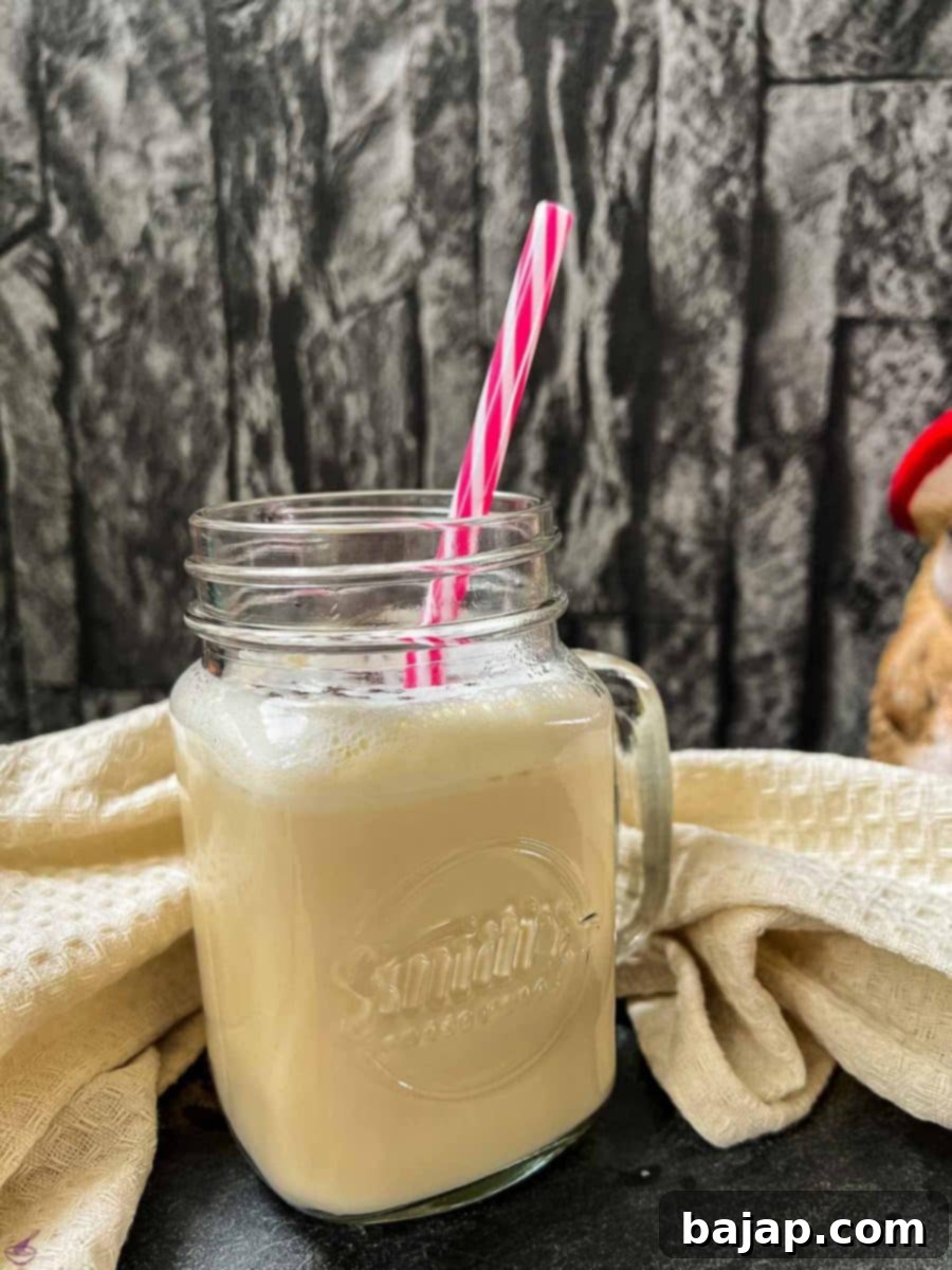 Easy 2 Ingredient Caramel Milk 2 Drinking glass with plastic straw and ready to drink caramel milk. Beige linen in the back.