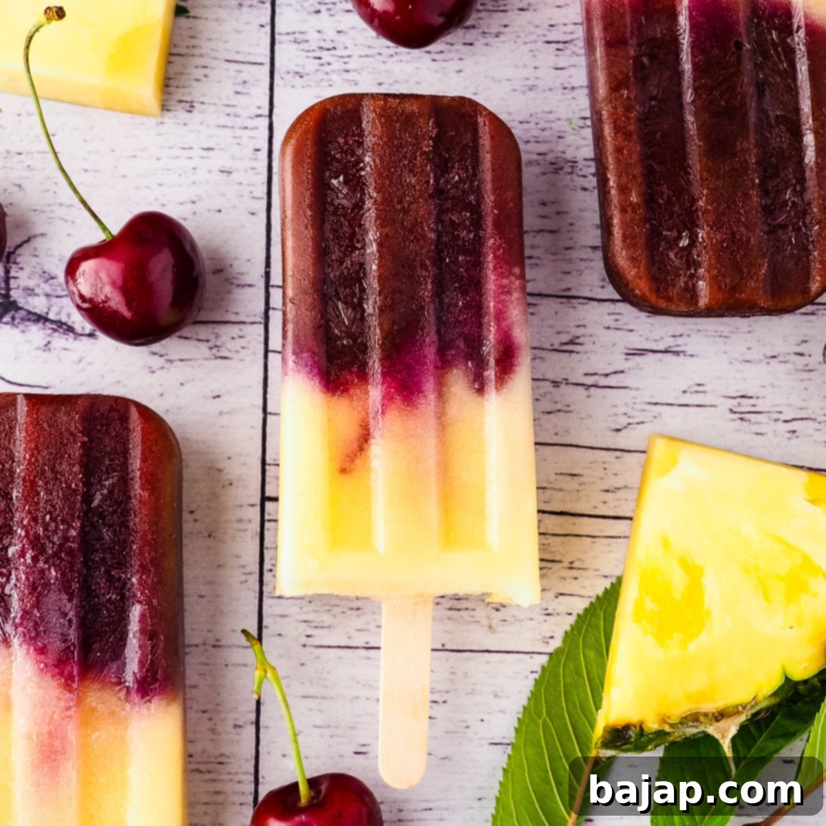 Vibrant pineapple cherry popsicles on a cooling rack.