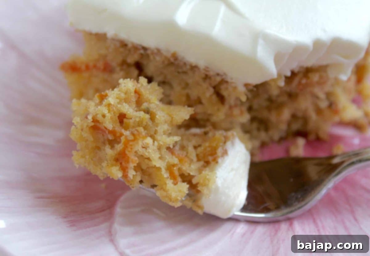 A slice of moist pineapple carrot cake with generous cream cheese frosting.