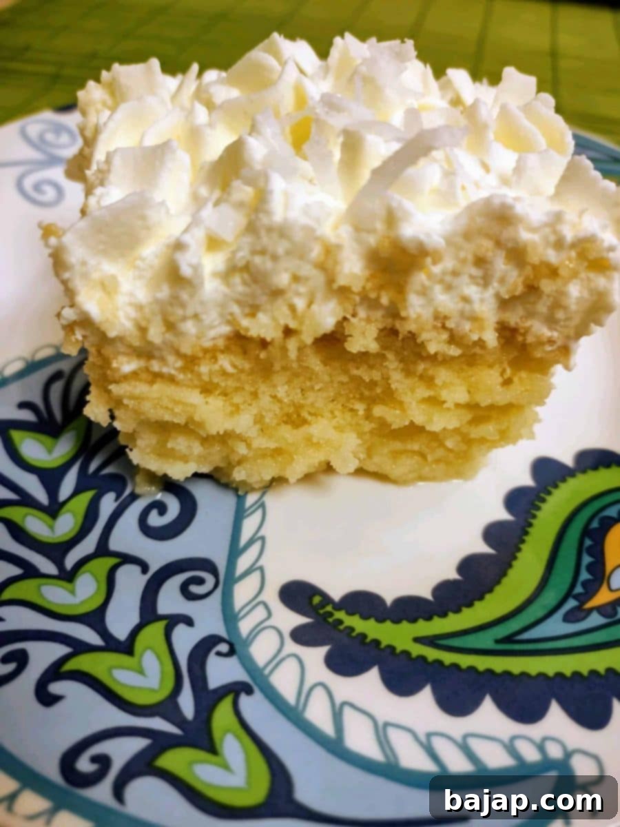 A slice of boozy Piña Colada Tres Leches Cake on a plate.