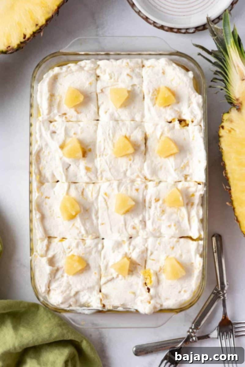 A delicious pineapple poke cake with whipped topping and coconut flakes.