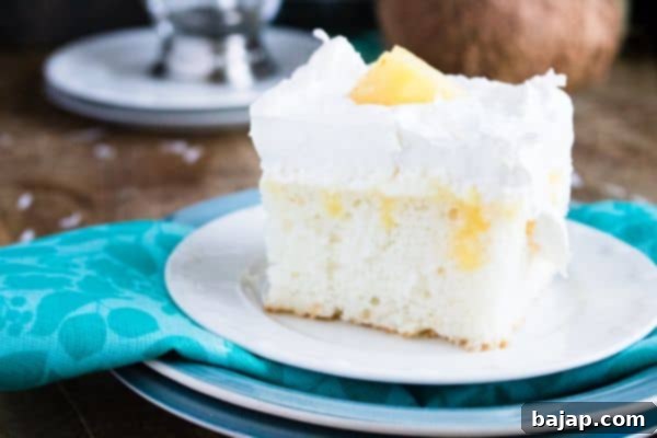 A slice of mouth-watering Pina Colada Poke Cake with whipped cream and cherry garnish.