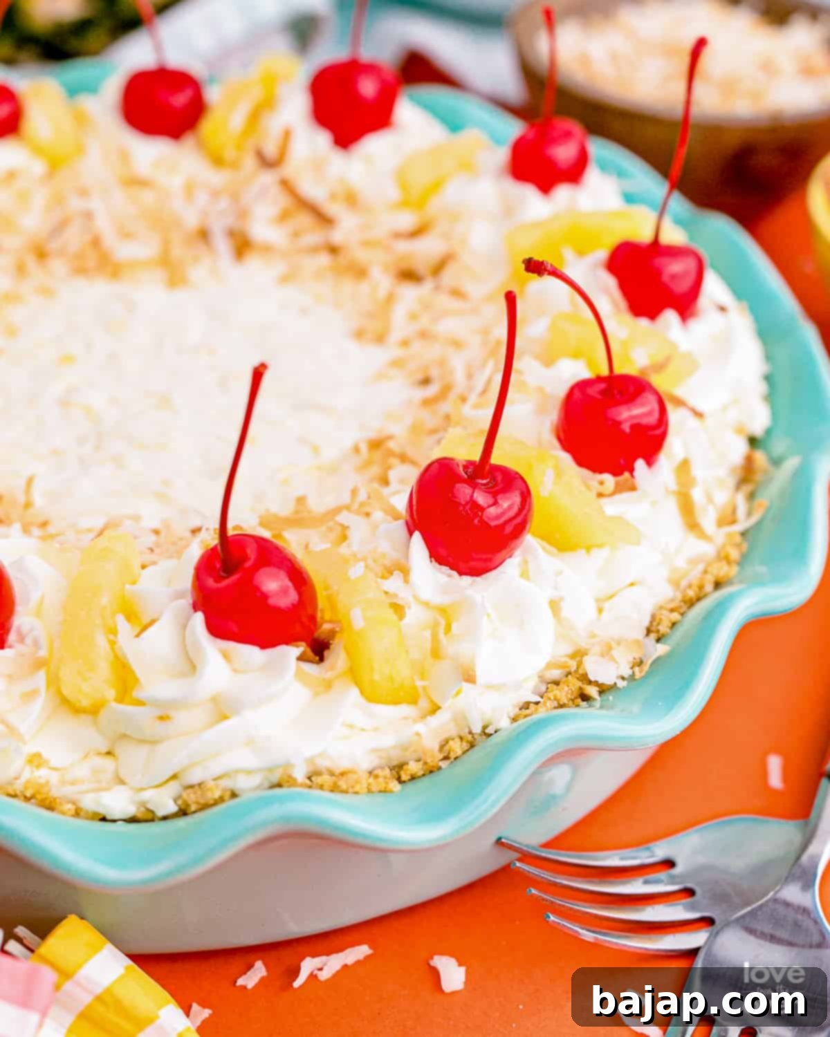 Slice of Pina Colada Pie on a white plate, garnished with whipped cream and a cherry.