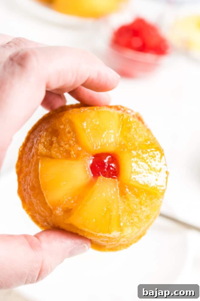 Individual pineapple upside down cupcakes on a cooling rack.