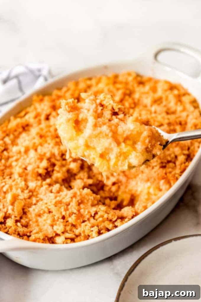 A savory-sweet pineapple casserole with a crumbly topping in a baking dish.