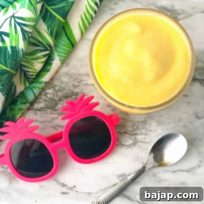 A glass of super quick pineapple Dole Whip smoothie with a spoon.