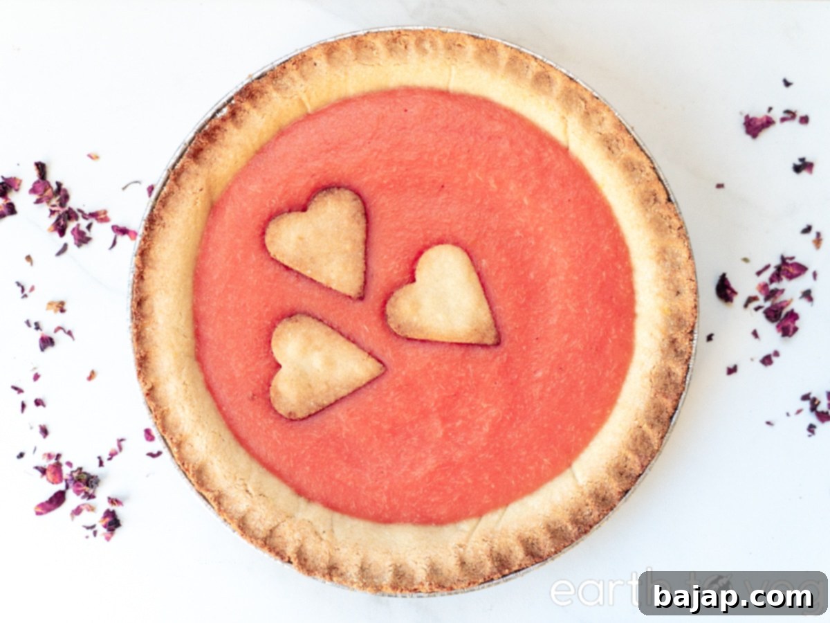 A vibrant, naturally pink pineapple pie, garnished with fresh mint.