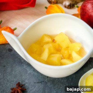 White ceramic bowl with apple compote. Decorated with apples, a cute hedgehog and orange flowers placed on the side.