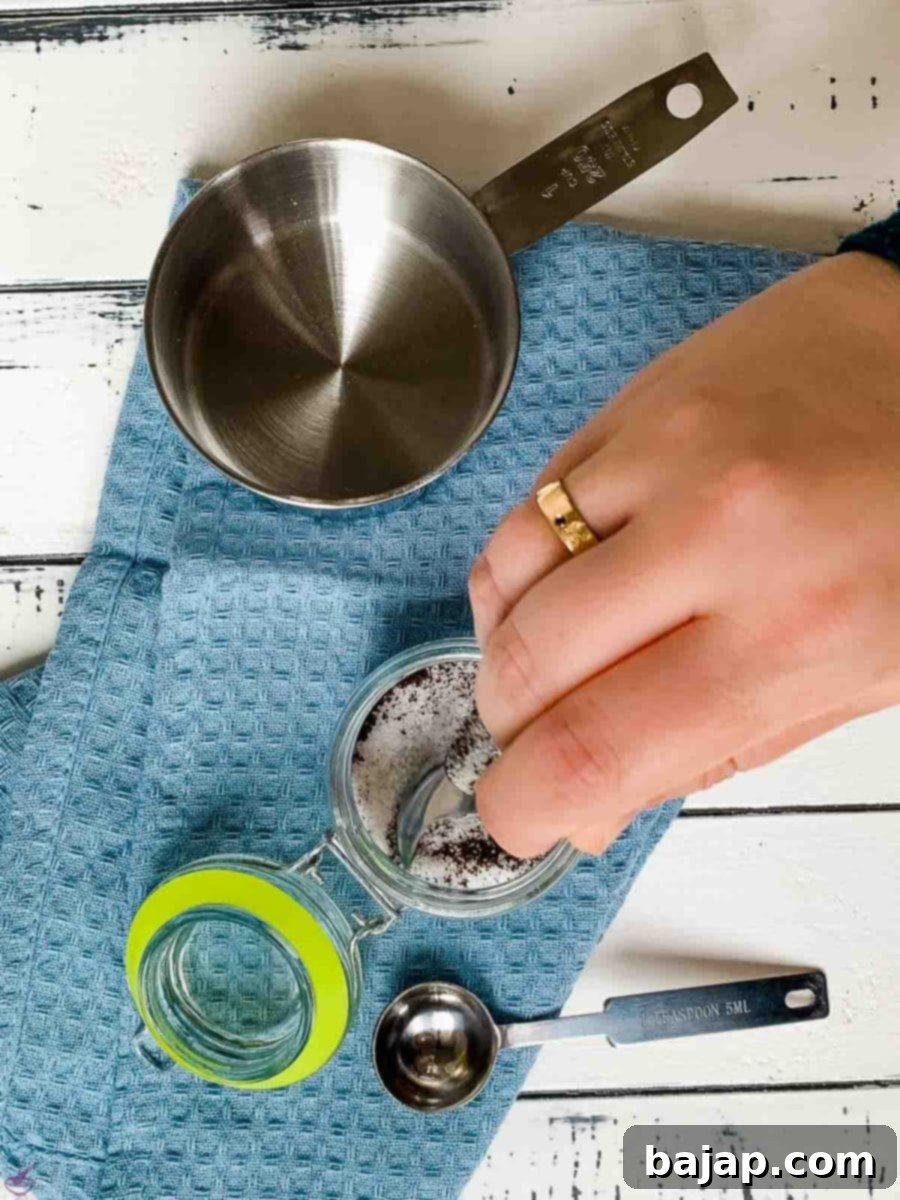 A hand vigorously shaking a closed preserving jar containing ground vanilla and sugar to combine them evenly.