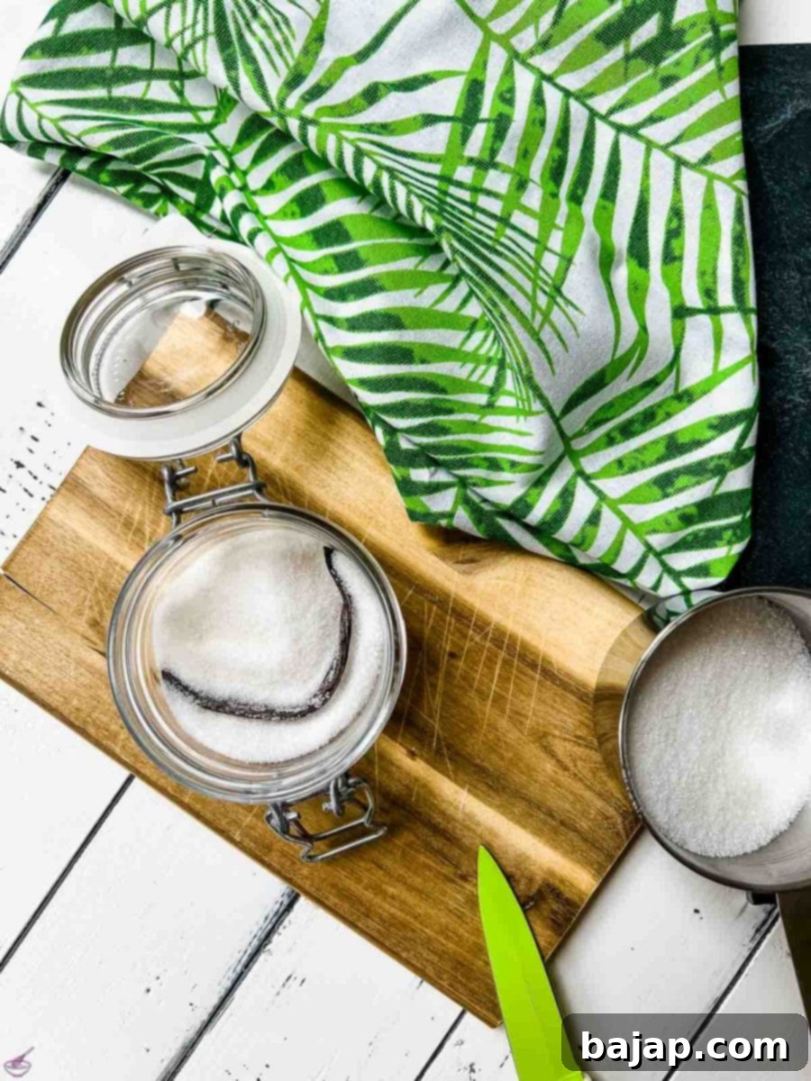 A scraped vanilla bean settled into a jar of sugar, ready for the rest of the sugar to be added.