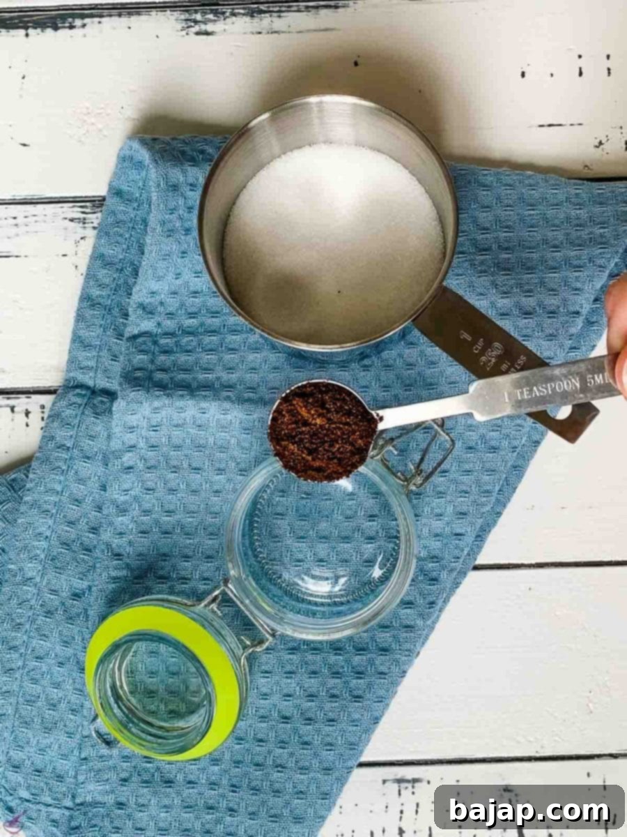 A teaspoon scooping out a pile of dark, aromatic ground vanilla powder.