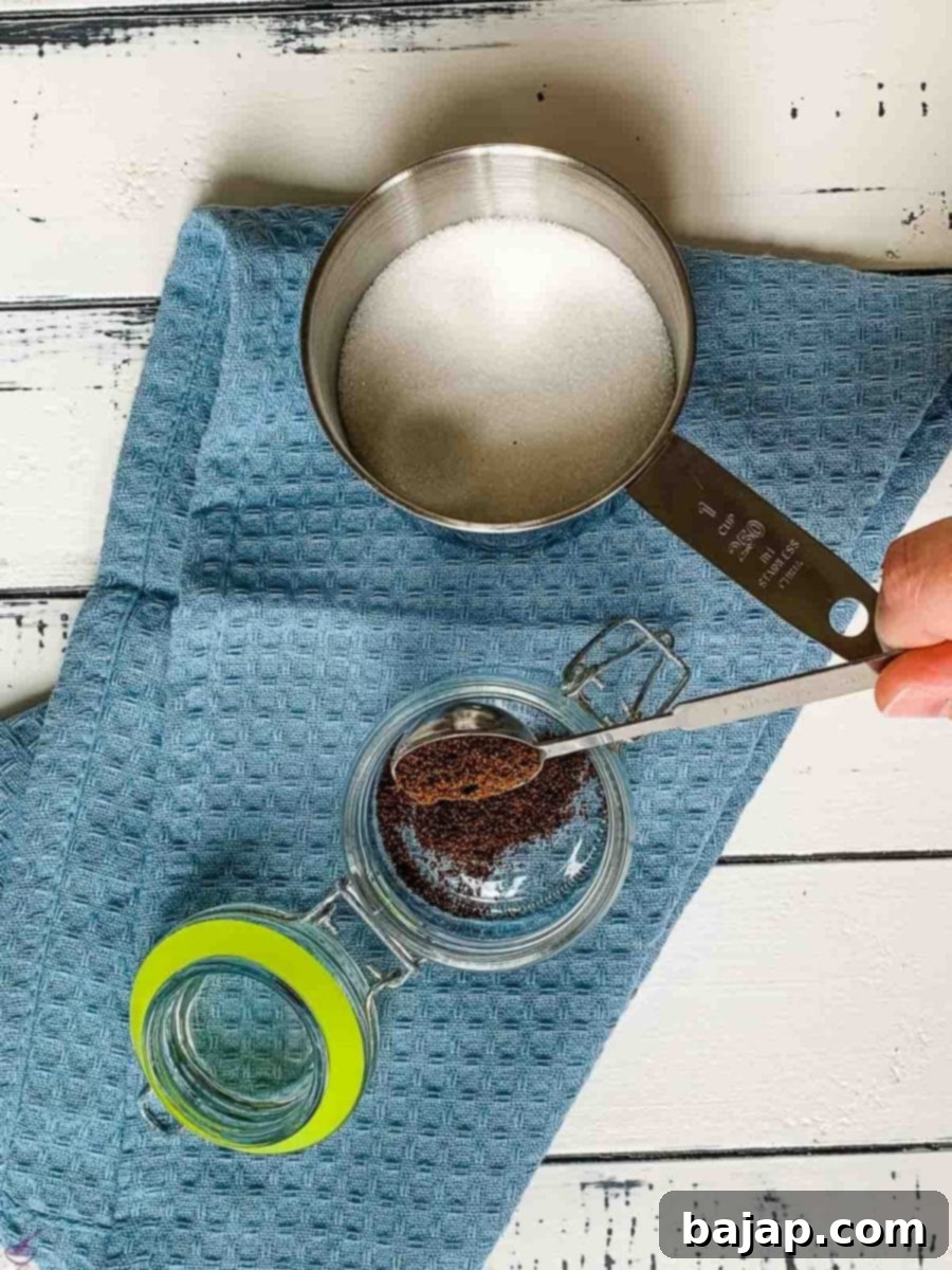 A hand pouring measured ground vanilla powder directly into a clean preserving jar.