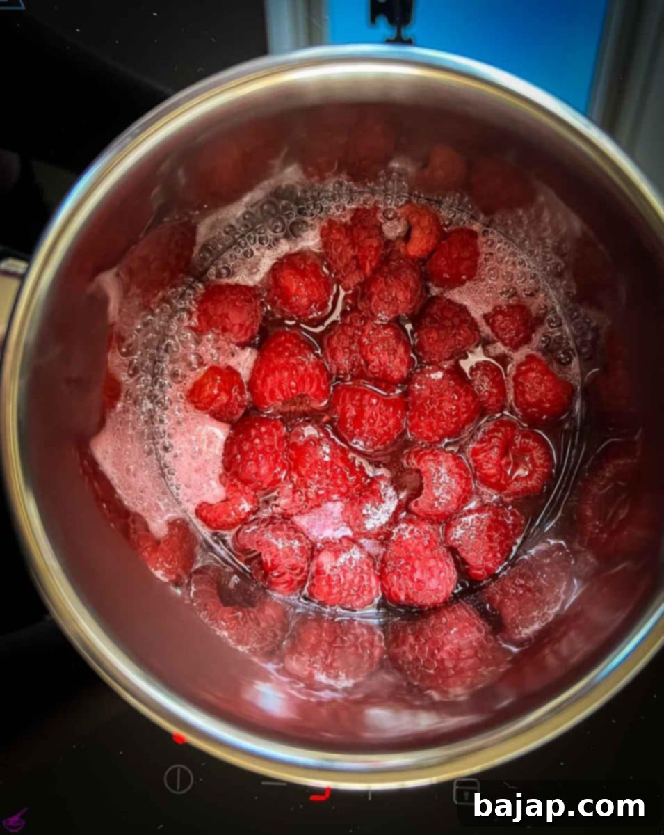 Bubbling water, raspberry, sugar mixture in a sauce pan. 