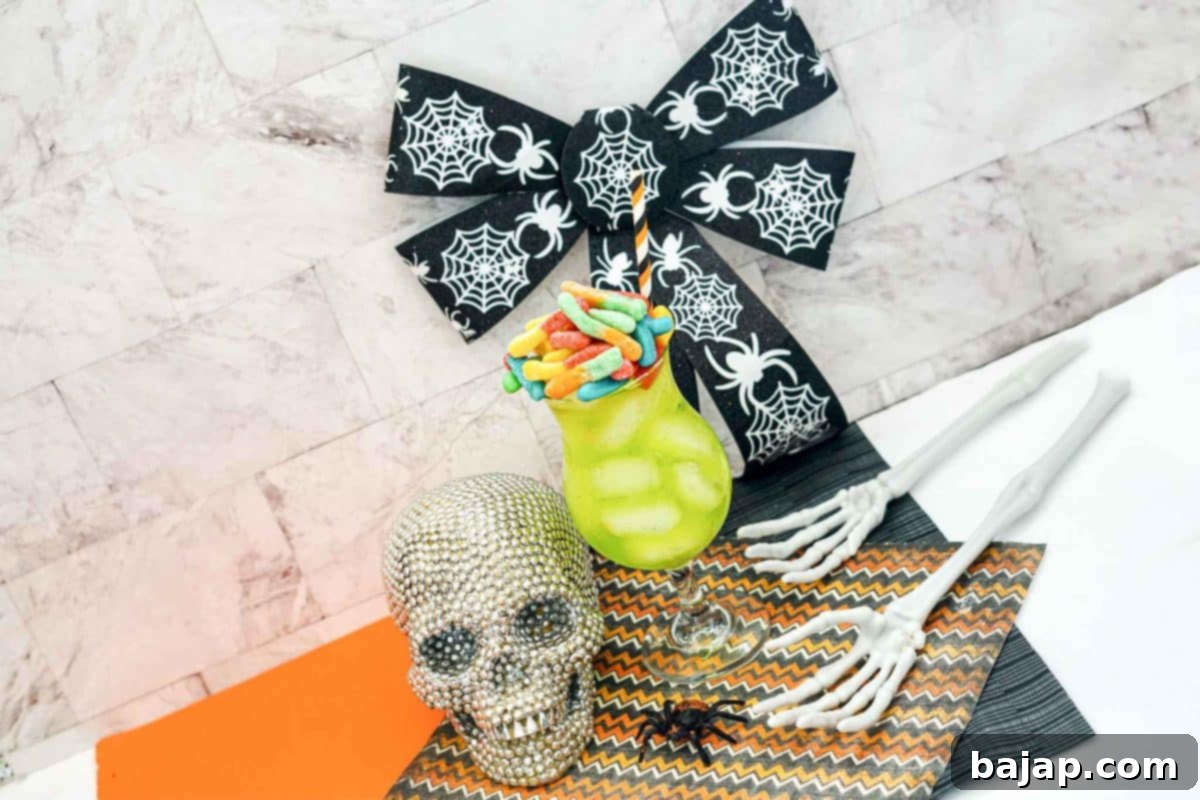 Easy Lime Green Rum Halloween Cocktail, made with rum, green Hawaiian Punch, and garnished with gummy worms.