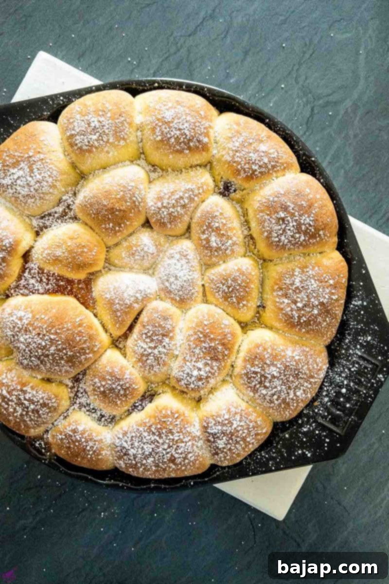 Finished baked Buchteln generously sprinkled with powdered sugar, ready for serving.