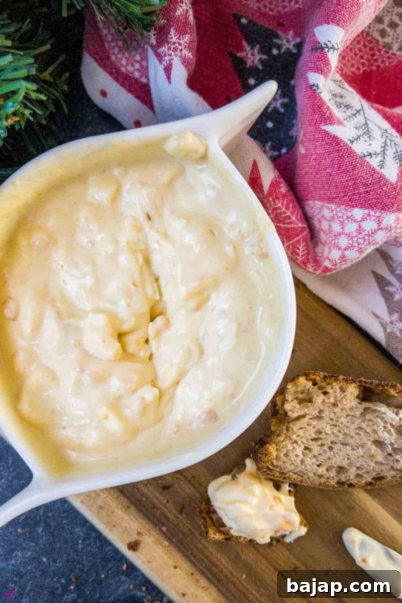 White bowl with egg salad spread and coated bread on brown board.