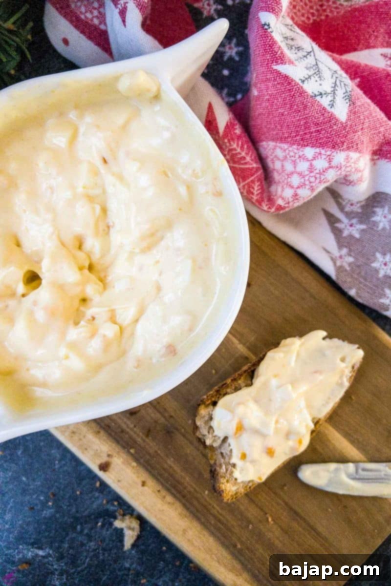 White bowl with egg salad spread and coated bread on brown board.