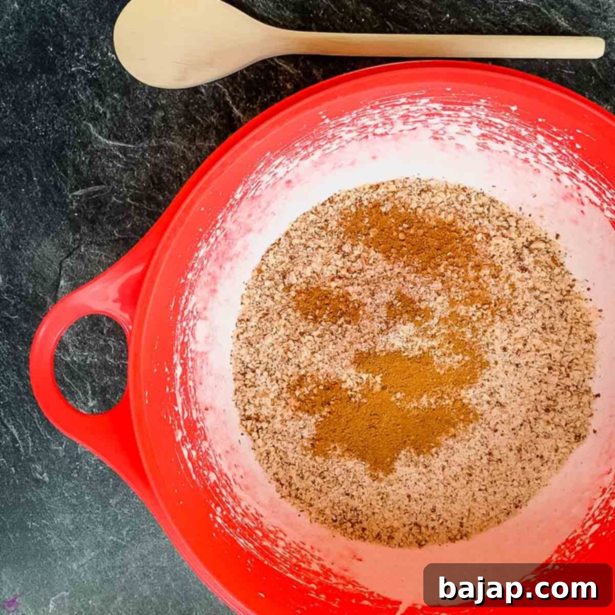 Mixing all ingredients for cinnamon stars with a wooden spoon.