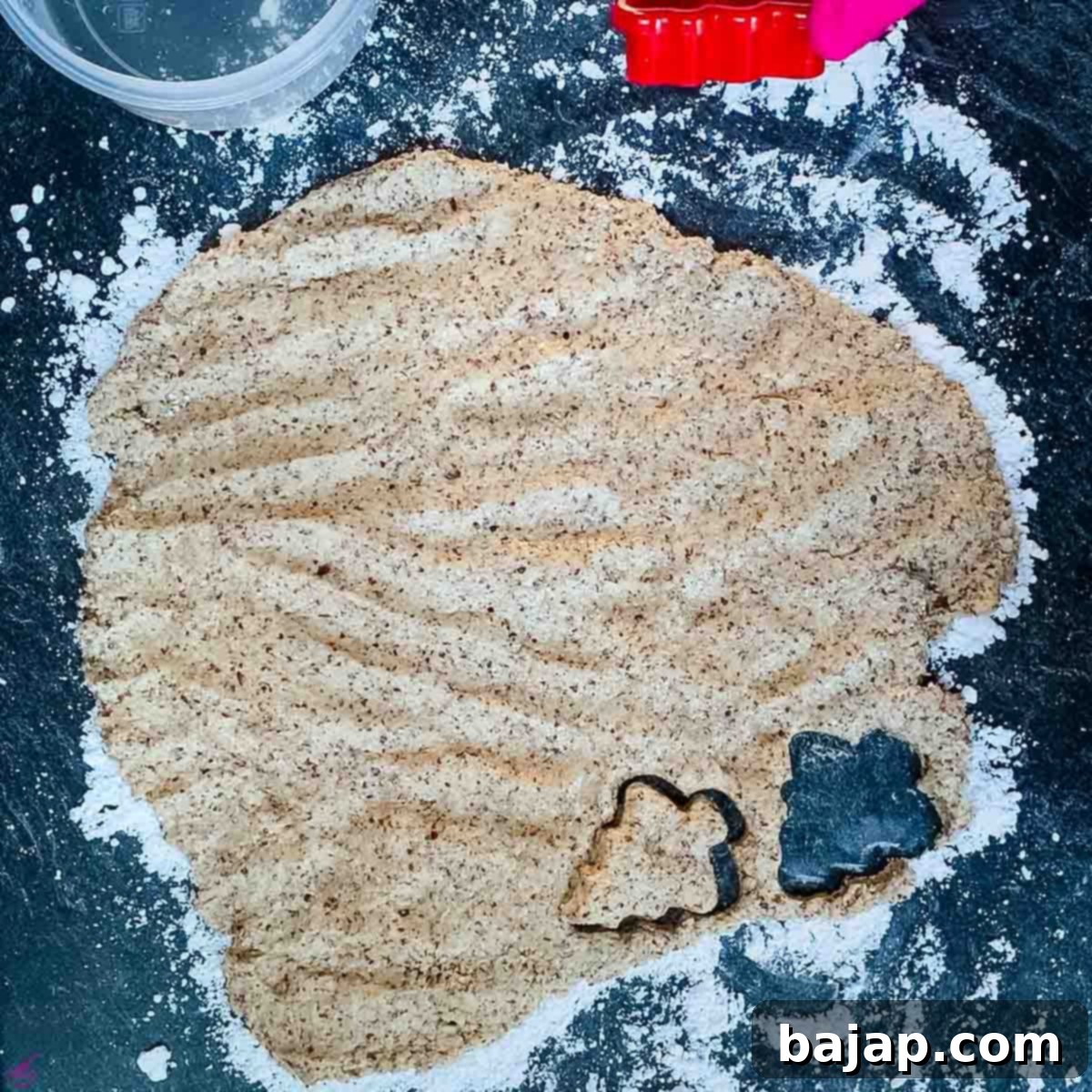 A tree-shaped cookie cutter pressing into the cinnamon star cookie dough.