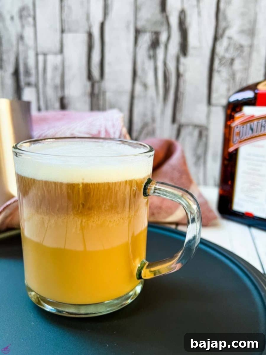Cointreau coffee with a beautiful layered pattern, garnished with an orange slice and cinnamon stick.
