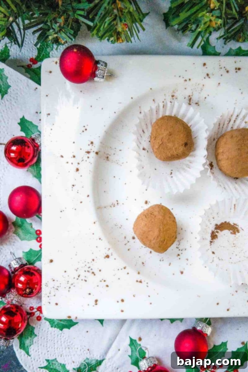 Scrumptious Biscoff truffles on white plate. Decorated with red Christmas baubles on the side.