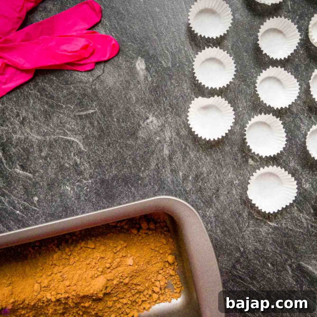 Chocolate paper cups, disposable gloves, and pan with raw Criollo cacao powder.
