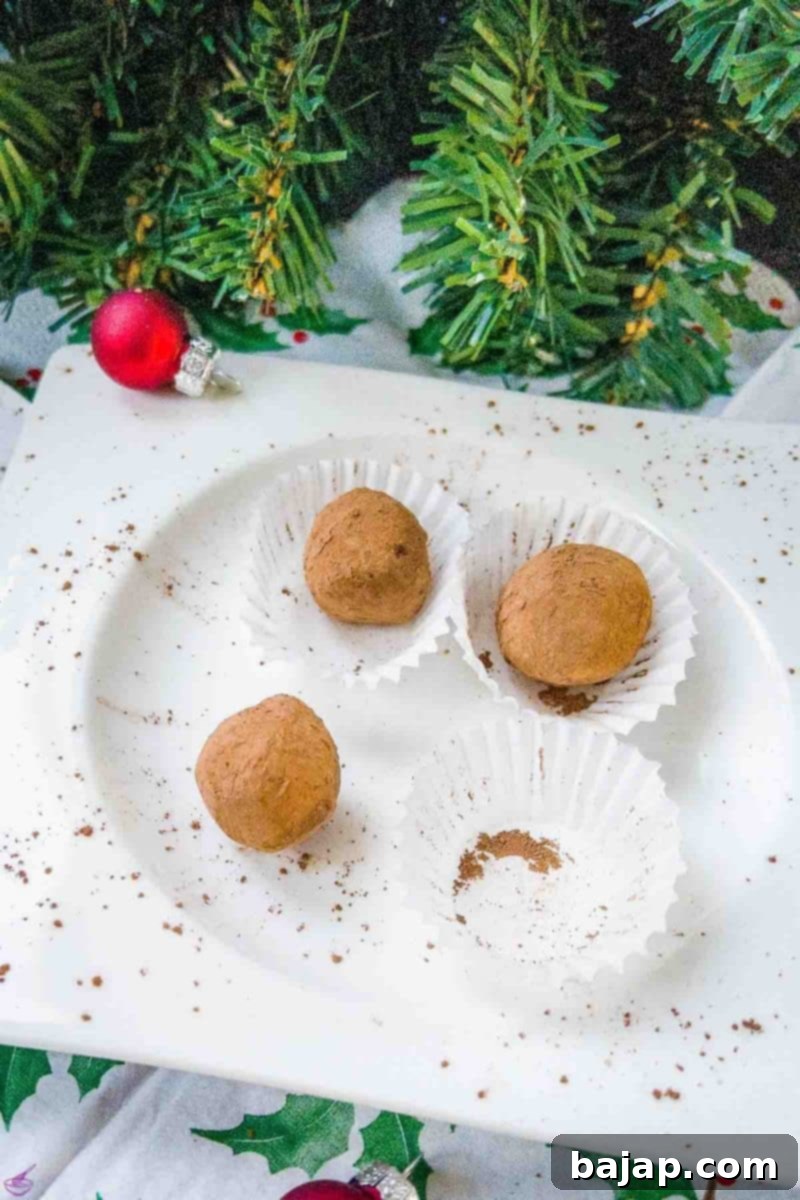 Scrumptious Biscoff truffles on white plate. Decorated with red Christmas baubles on the side.