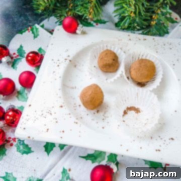 Scrumptious Biscoff truffles on white plate. Decorated with red Christmas baubles on the side.