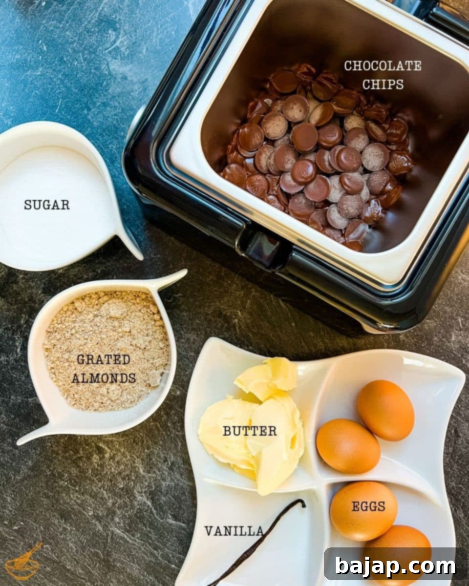 A selection of simple, high-quality ingredients laid out for making flourless chocolate cake: unsalted butter, sugar, vanilla pod, eggs, semisweet chocolate chips, and grated almonds.