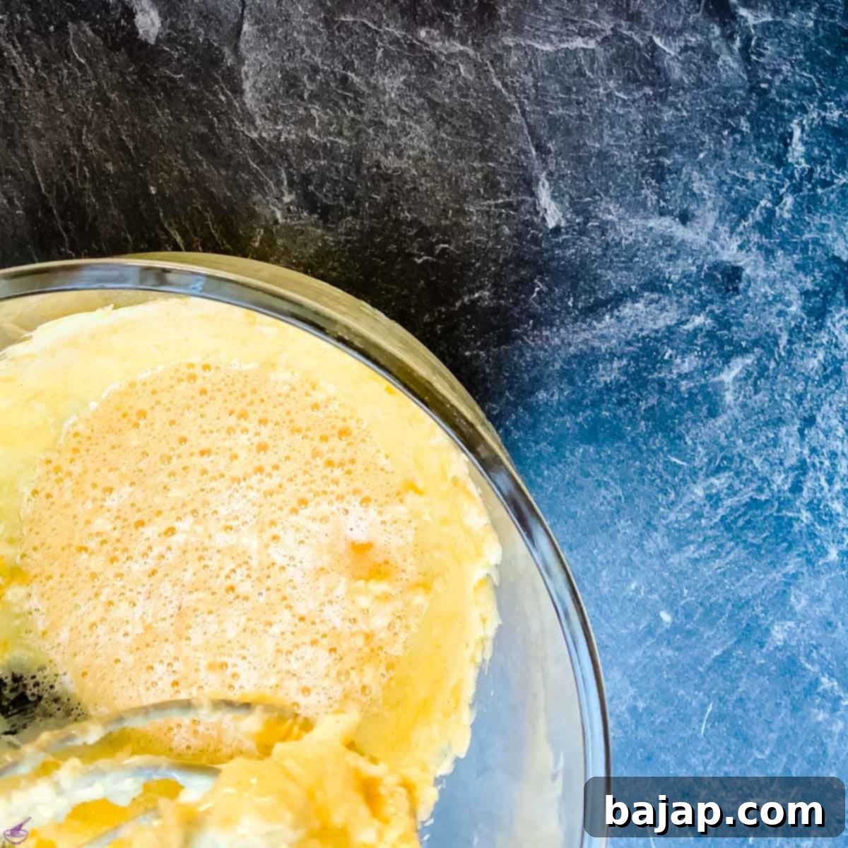 A fluffy, pale yellow cake batter mixture in a stand mixer bowl, indicating proper creaming of butter, sugar, and vanilla.