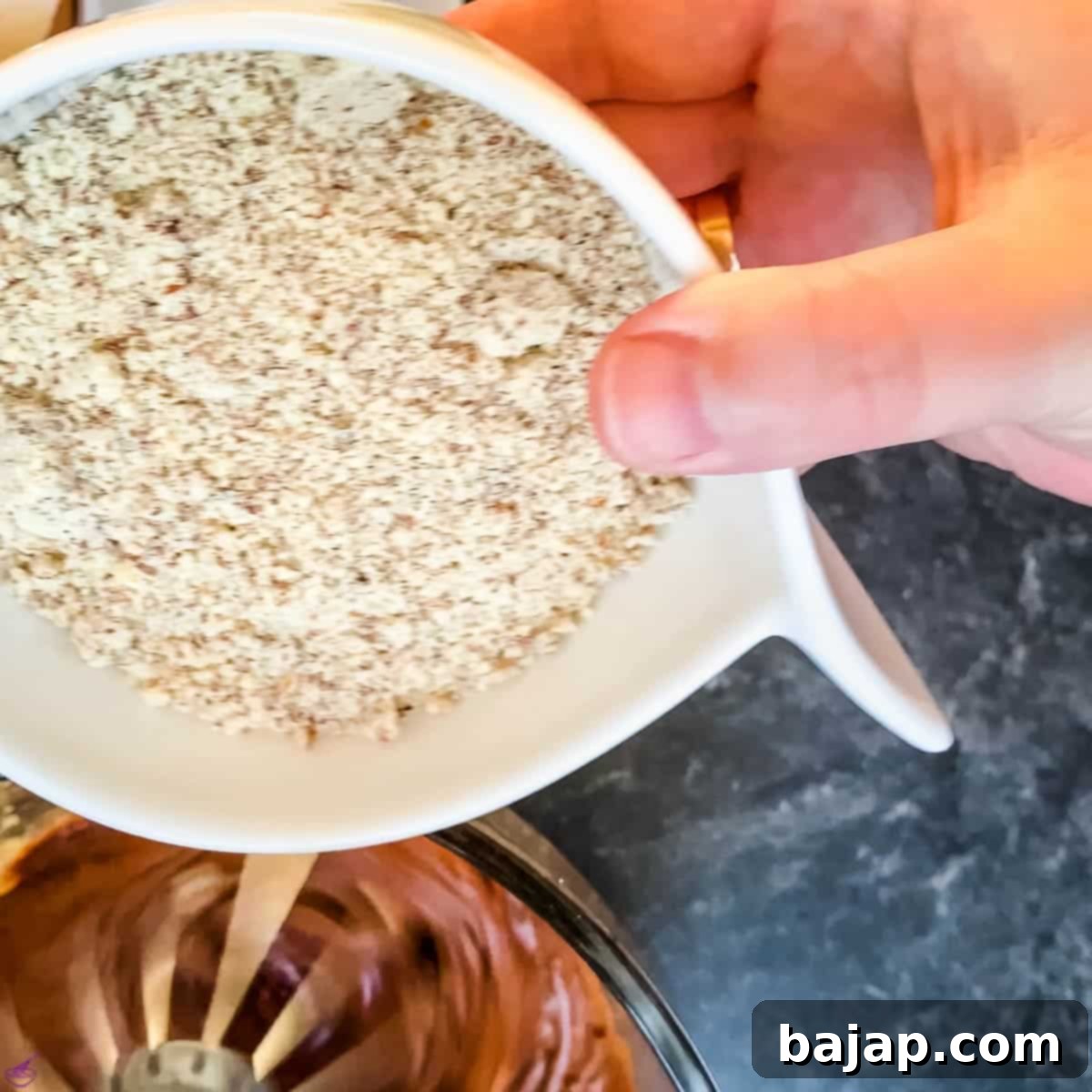 Grated almonds being added to the chocolate cake batter.