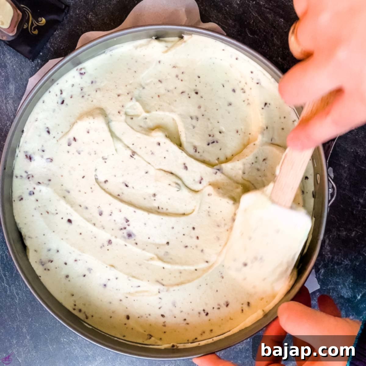 Spreading the mint cream cheese filling evenly over the Oreo crust in a springform pan.