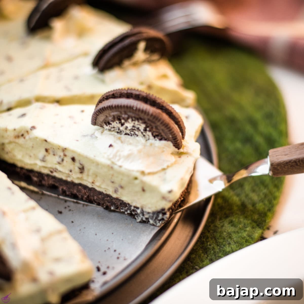 A whole no bake mint chocolate cheesecake with Oreo crust and After Eight pieces inside the cream cheese filling, ready to be served.