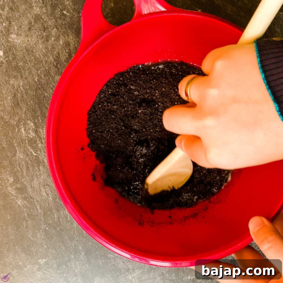 Melted butter being combined with Oreo crumbs in a mixing bowl.