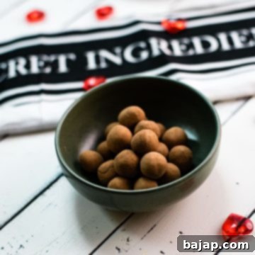 Delicious marzipan potatoes in a dark green bowl on white wooden ground.