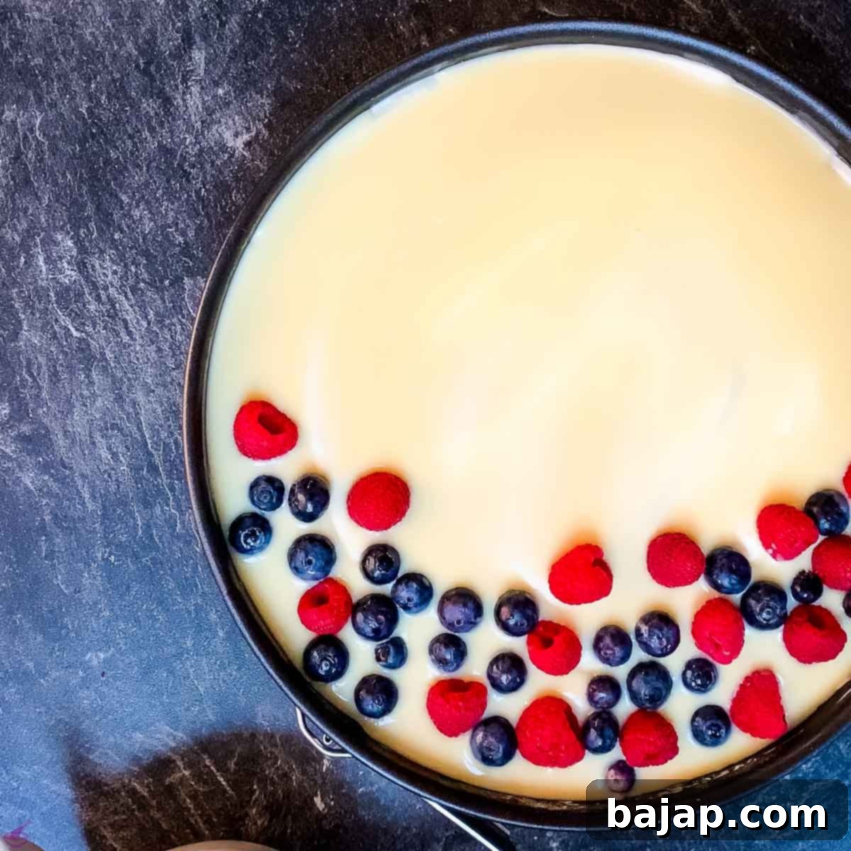 Detailed shot of the decorated 4th of July no-bake cheesecake, highlighting the fresh raspberries, blueberries, and chocolate zebra rolls.