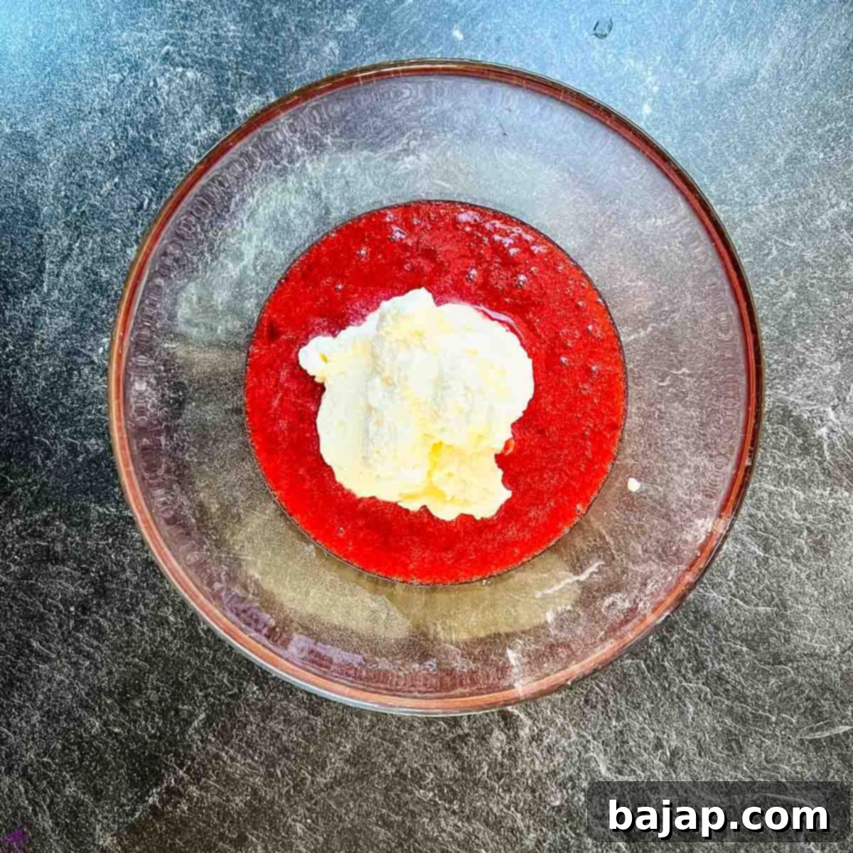 Gently fold the stiff whipped cream into the sweet strawberry purée using a whisk or rubber spatula.