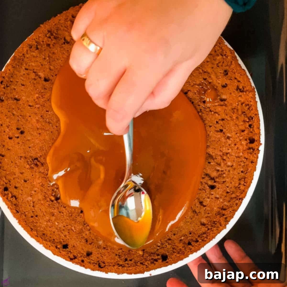 Spread the warm apricot jam on the first cake layer.