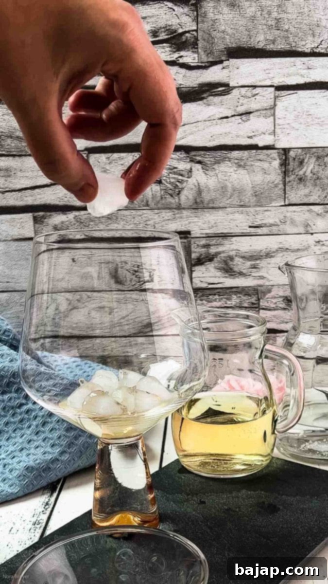 Adding ice cubes to a glass for the lavender spritz.