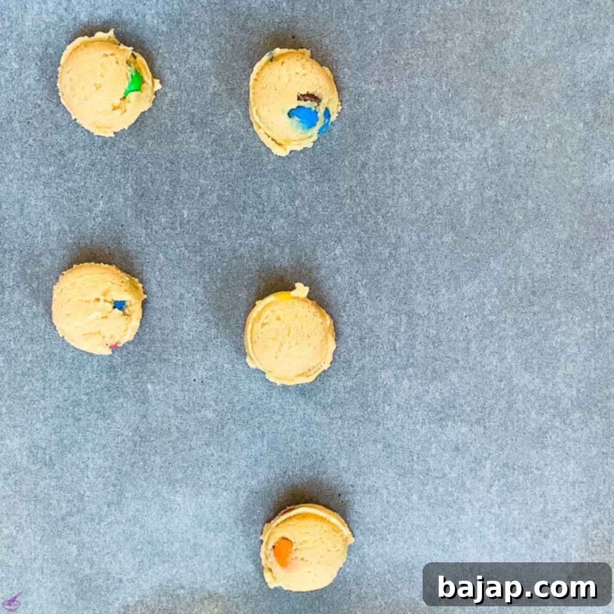 Neatly spaced cookie dough balls waiting on a parchment-lined baking sheet before baking.