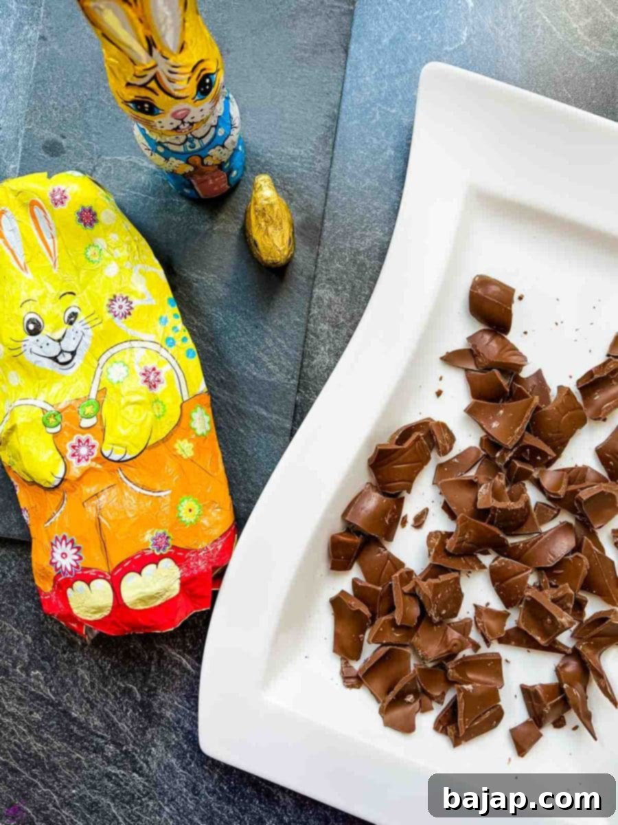 A hand breaking a chocolate Easter bunny into small pieces for the ice cream.