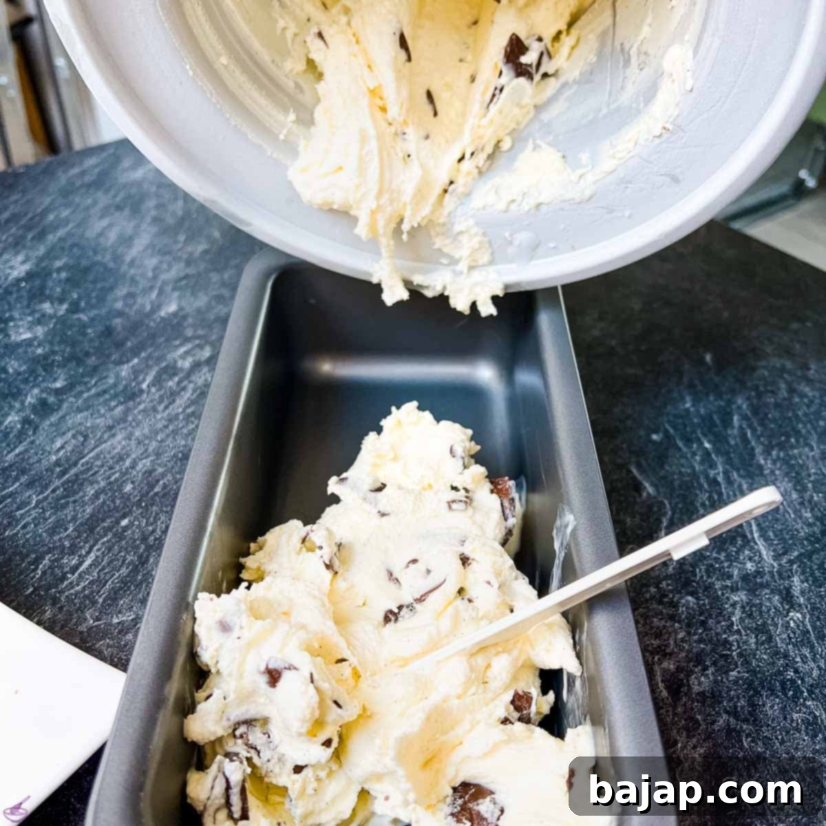 Filling the freshly churned ice cream mixture into a loaf pan for freezing.