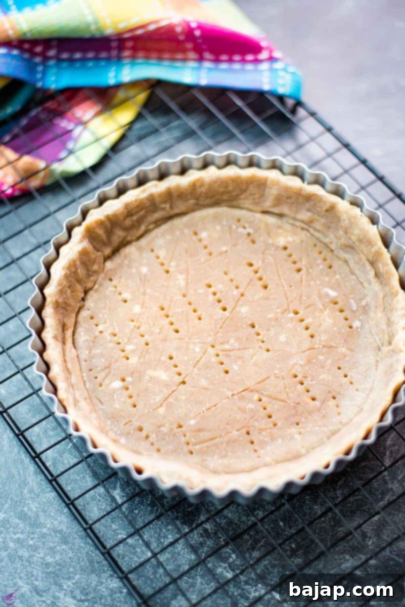 A golden-brown walnut tart crust, beautifully shaped and ready for filling, sits in a tart pan, promising a delicious homemade dessert.