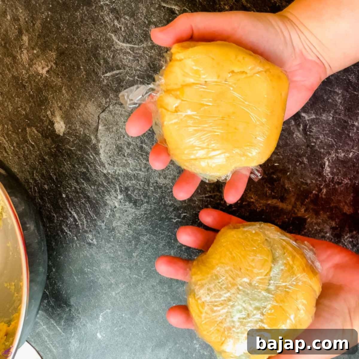 Two halves of the freshly prepared walnut tart dough, each neatly wrapped in cling film, ready for chilling in the refrigerator.