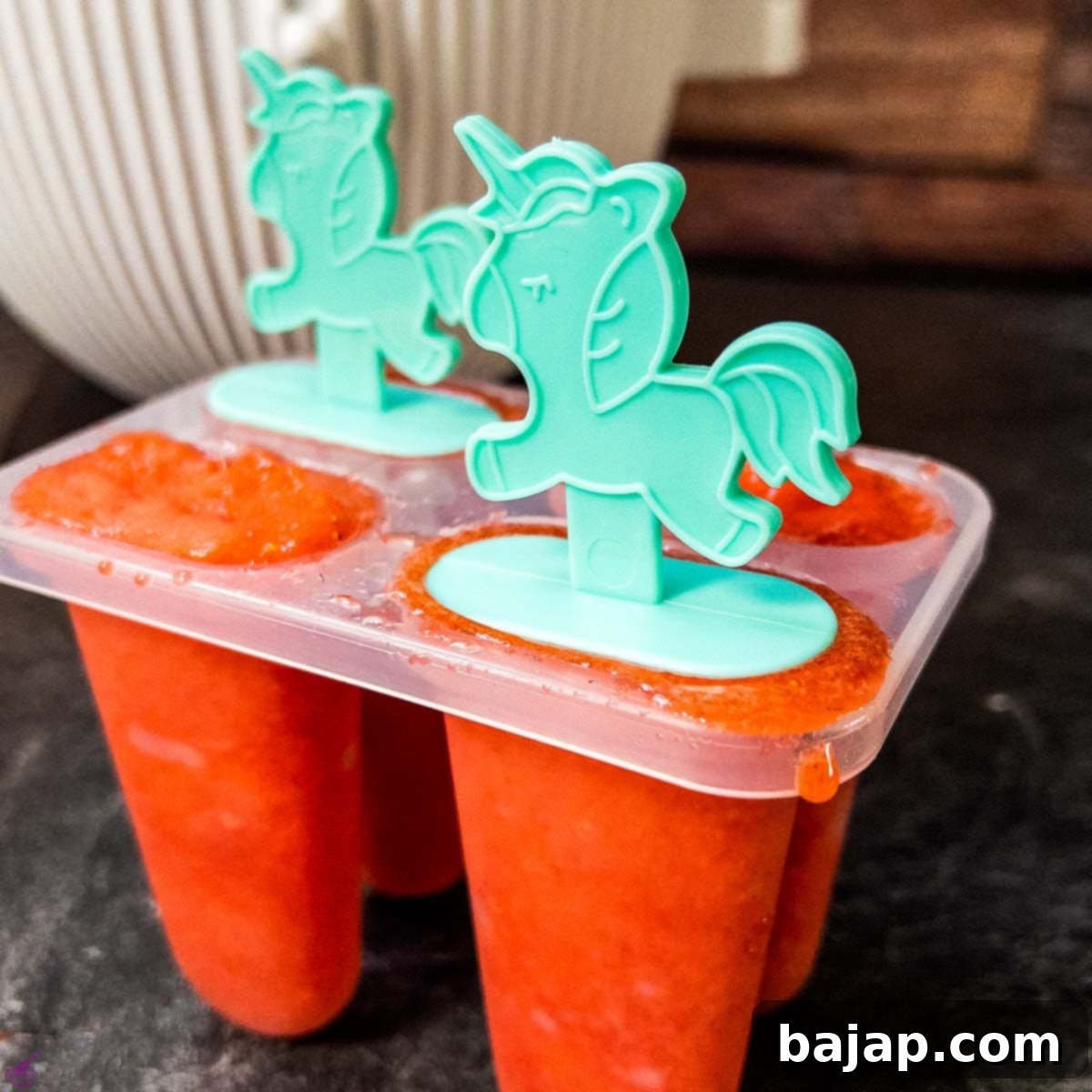 Popsicle molds being filled with the strawberry mixture.